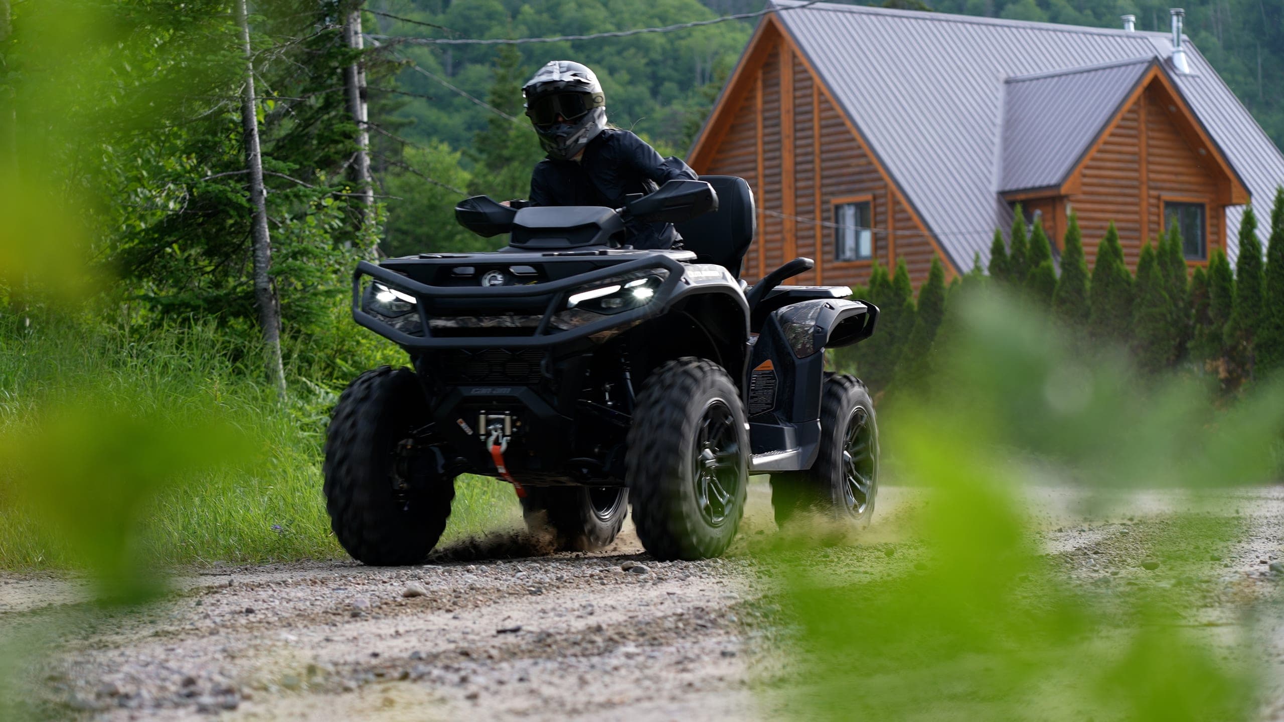 A Nomad360 ATV speeding past a log cabin